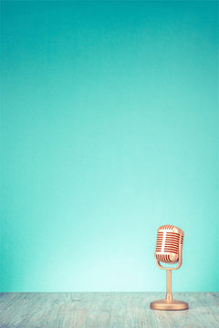 Retro golden microphone for press conference or interview on table front gradient mint green wall background. Vintage old style filtered photo