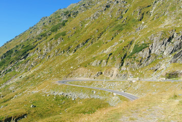 A view to a curve of the most famous, spectacular and dangerous road in Europe is a Transfagarasan road in Carpathian mountains, Romania. Potentially dangerous curve on a mountain road on sunny day.