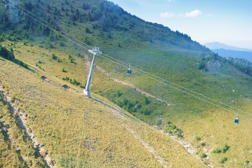 A landscape of Carpathian mountains with a cabin car moving along, a view from cableway cabin.