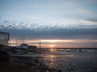 Obraz na płótnie Canvas sun set sky dramatic clouds sea front beach harbor marina boats moored landscape