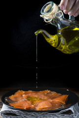 Cocinero aderezando un plato de pescado con aceite de oliva virgen, pescado marinado para una...