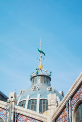 VALENCIA, SPAIN - FEBRUARY 3, 2016: A modernist rich decorated dome of a central market hall with a sculpture of a green parrot on sunny day. Copy space for text.