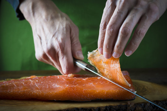 Cocinero cortando lonchas de salm&oacute;n en salaz&oacute;n para marinar y preparar sushi y otras comidas
