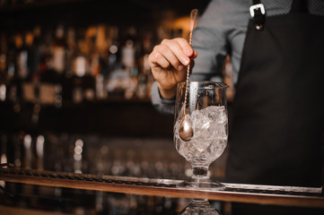 Barman stirring ice cubes with help of spoon