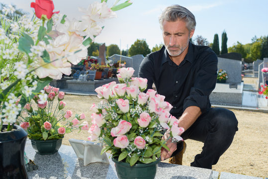 man putting fresh flowers in the graveyard