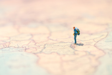 Miniature people: small figurine of lonely young traveler walking on big map