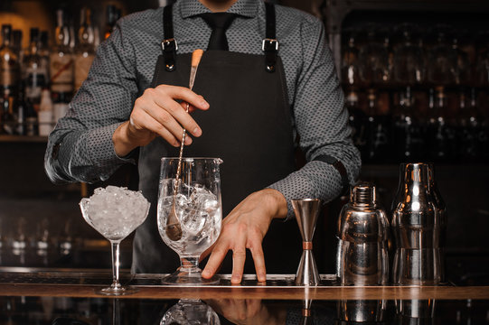 Barman making a cocktail with help of the bar equipment