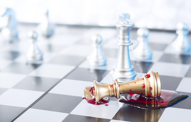 A conceptual photo with chess pieces and blood on a chessboard. Business, law or political concept, which could represent war of corporations, geopolitical situation and so on. Selective focus.