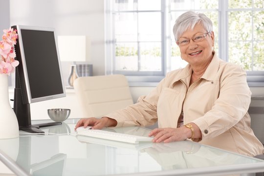 Happy old woman using computer at home