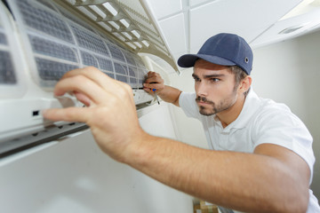 portrait of mid-adult male technician repairing air conditioner