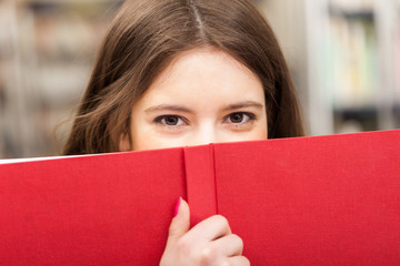 Teen looking from behind a book