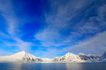 White snowy mountain, blue glacier Svalbard, Norway. Ice in ocean. Iceberg twilight, ocean. Pink clouds with ice floe. Beautiful landscape. Land of ice. Cold blue water nature. Rocky island with snow.