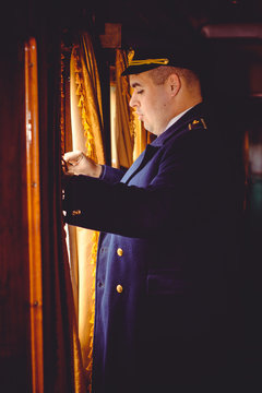 European or American train conductor is on his duty on a platform and other trains. Railway, steam trains, vintage trains .Train controller on the train, near a locomotive