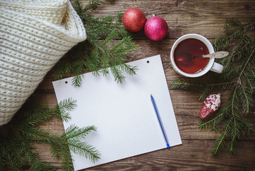 Winter picture: notepad with pen, cup of tea, fir branches, Christmas toys and scarf