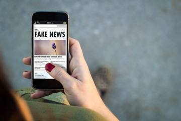 Woman walking smartphone fake news