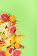 green background, with a set of multicolored citrus fruits, lie in a corner