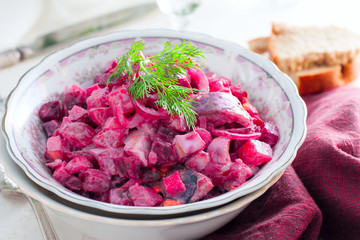 German traditional salad with beets, apple, egg and herring in a bowl, selective focus
