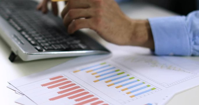 data entry - clerk working with statistical charts and typing on keyboard