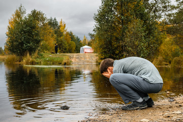 Man washing on the lake bank in overcast day, Leningrad Region, Russia