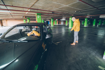Fototapeta premium young woman parking car in underground parking with man help