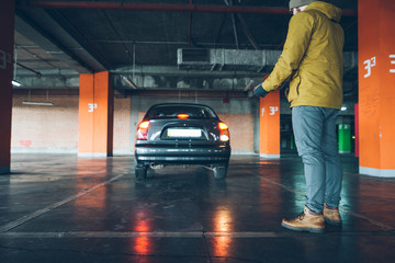 young woman parking car in underground parking with man help