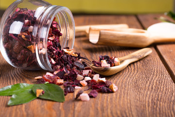 Herbal aroma fruit tea dry leaves on spoon and glass pot on wooden background