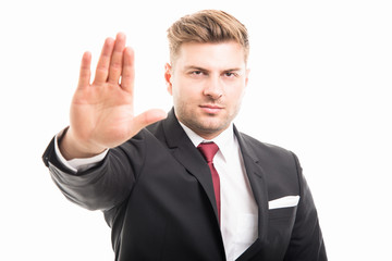Portrait of handsome corporate business man showing stop gesture