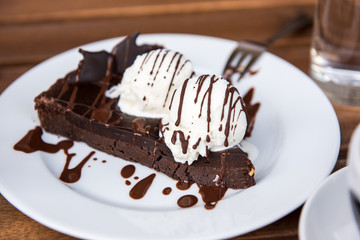 Brownie cake with vanilla ice cream served on white plate 