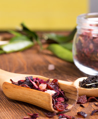 Herbal aroma fruit tea dry leaves on spoon on wooden background