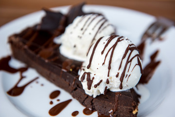 Brownie cake with vanilla ice cream served on white plate 
