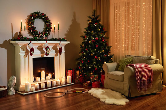 Christmas room interior design, Xmas tree decorated dy lights presents gifts toys, candles and garland lighting indoors fireplace. Christmas holiday living room. New year design.