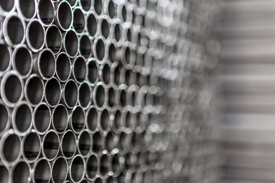 Industrial background. Close up of internal metal pipes in a warehouse. Stack of new and shiny steel pipe in factory.