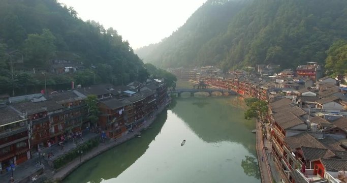 Top view or aerial shot of famous ancient town in Fenghuang County, China. Flying over Green River, hills and houses of the village. Travel,destination and world heritage concept.