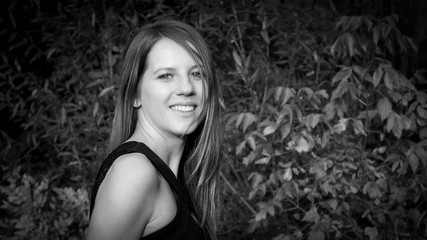 White and Black Portrait of Pretty Beautiful Young Woman with Charming Smile and Long Hair in the Park During a Day.