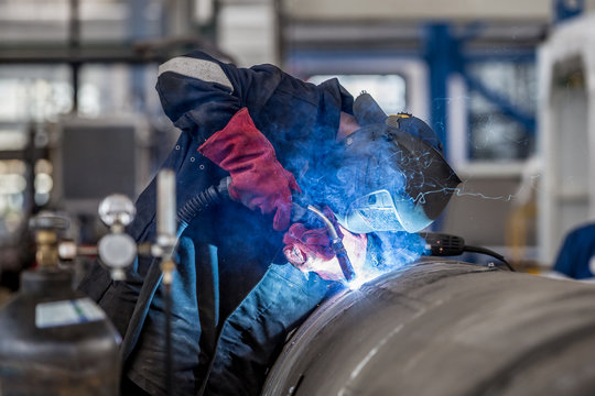 The welder in the mask welds the metal part