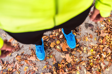 Young runner in autumn park standing on concrete path.