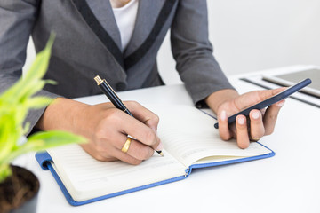 Finance managers task use smart phone and note or check for about finance cost at office, Businessman recheck new plan financial graph data. Business and strategy investment concept.