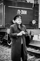 European or American train conductor is on his duty on a platform and other trains. Railway, steam trains, vintage trains .Train controller on the train, near a locomotive

