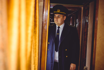 European or American train conductor is on his duty on a platform and other trains. Railway, steam...