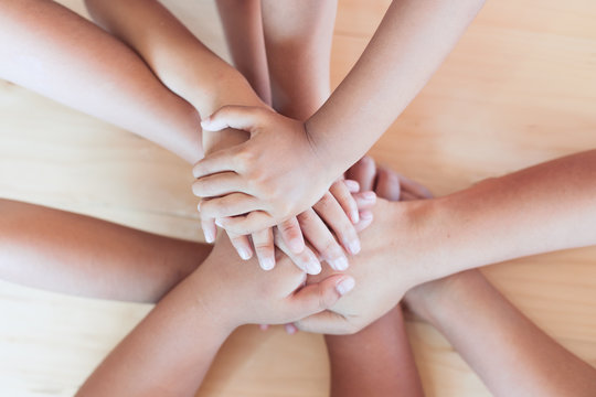 Parent and children holding hands together on wooden background. Family and friend stack hands showing unity and teamwork