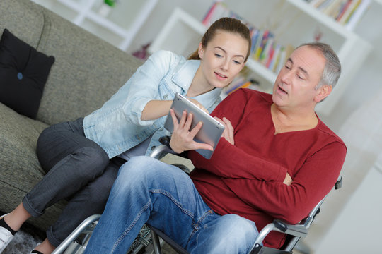young woman helping a senior man to use a tablet