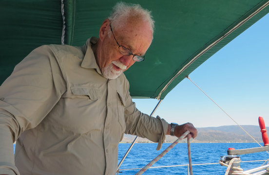 Close-up: An Elderly Man Unravels A Rope On A Sailing Boat. It Is Never Too Late To Master Skills Of Sailing. Concept: Active Elderly People.