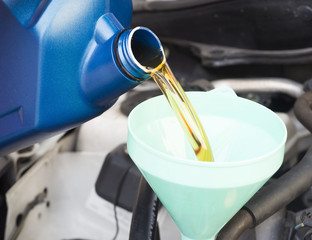 Close up pouring oil to car engine, maintenance concept
