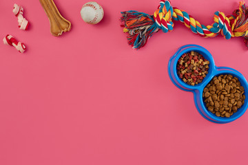Fototapeta na wymiar Toys -multi coloured rope, ball, dry food and bone. Accessories for play on pink background top view