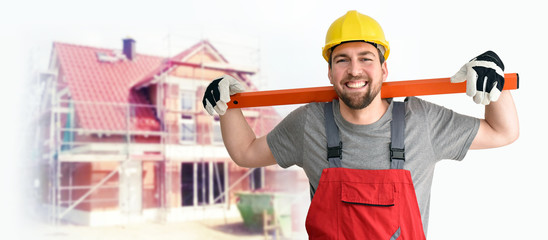 Hausbau - fröhlicher Handwerker in Berufsbekleidung vor einer Baustelle // House building -...