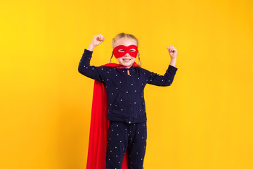 Superhero little girl in a red raincoat and a mask