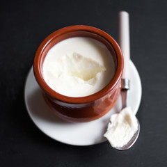 Sour  cream or natural  Cottage cheese curd in clay pot on dark  background. Traditional Cuajada yogurt cream