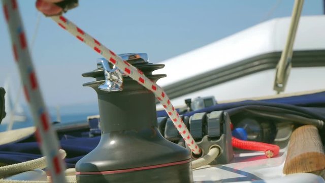 Sailor pulling red and white striped roap to reel in front sail called flock. Filmed on sailing in Croatia in slow motion hd.