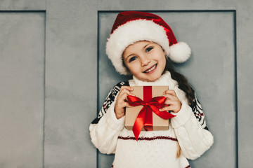 Little cheerful girl holding gift box, Santa Claus surprise, Christmas morning