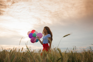 Girl with balloons in wheat field